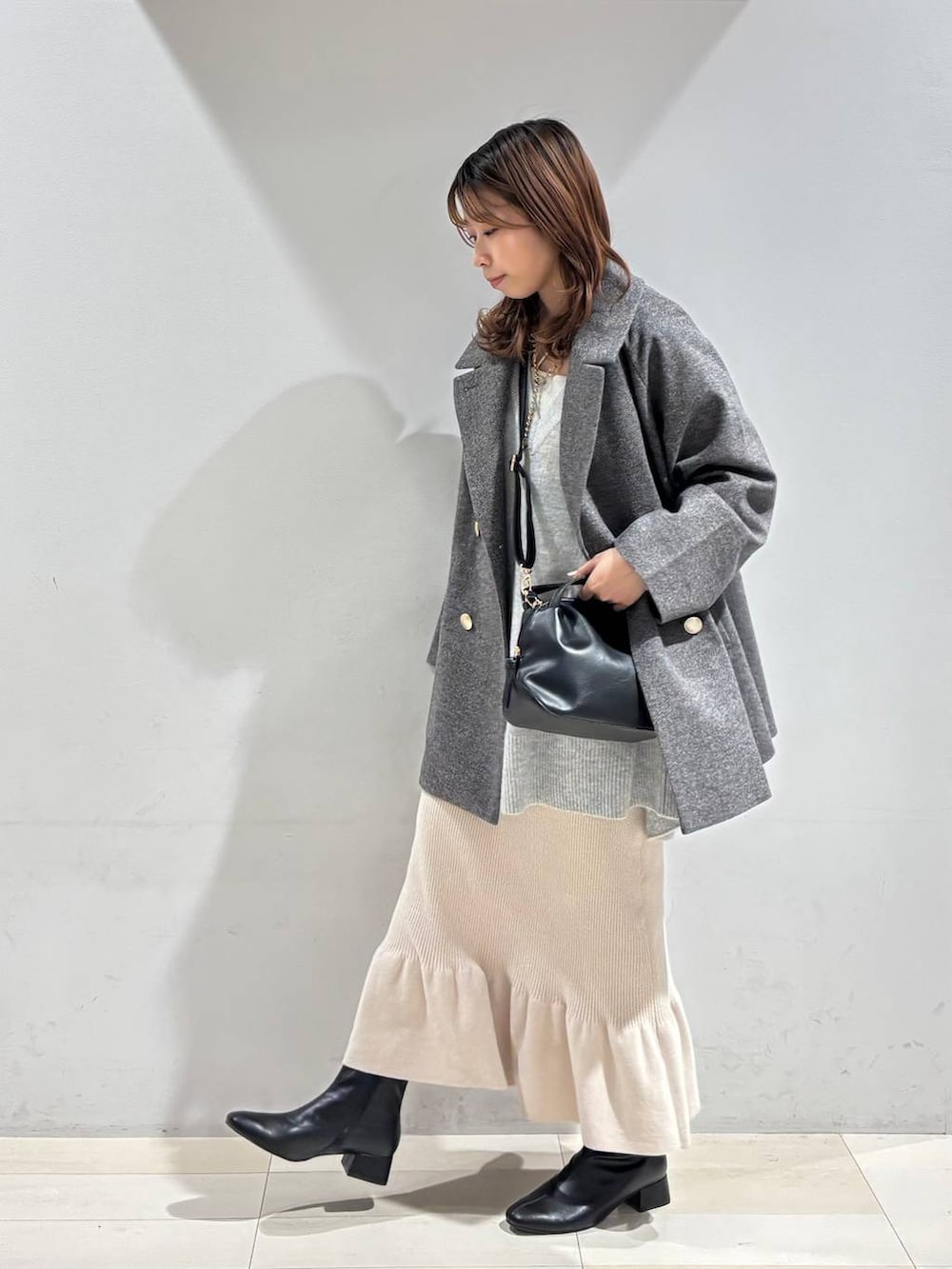 ブラック系のショルダーバッグ、グレー系のチェスターコート、グレー系のニット/セーターを着用したレディースの冬コーディネートの3枚目の写真