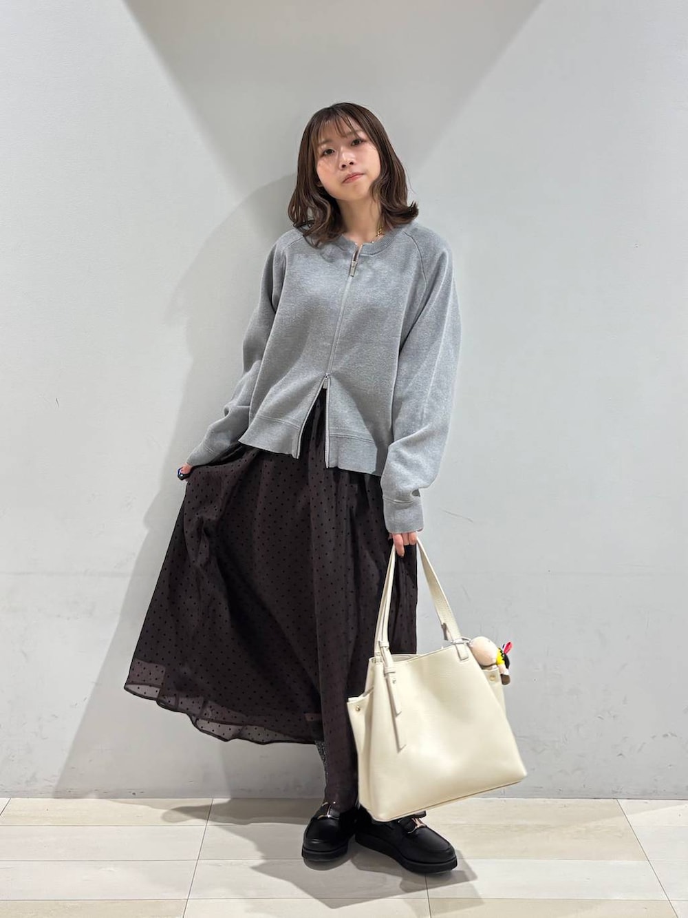 ブラック系のローファー、ホワイト系のハンドバッグ、ブラウン系のスカートを着用したレディースの春コーディネートの7枚目の写真