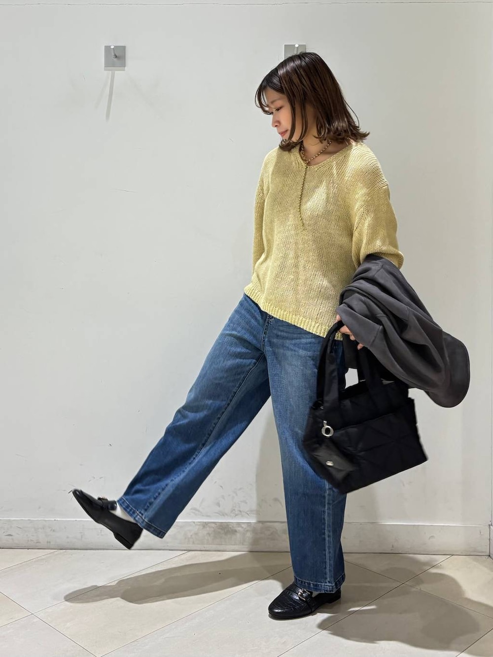 ブラック系のローファー、ブラック系のトートバッグ、ブルー系のデニムパンツを着用したレディースの春コーディネートの3枚目の写真