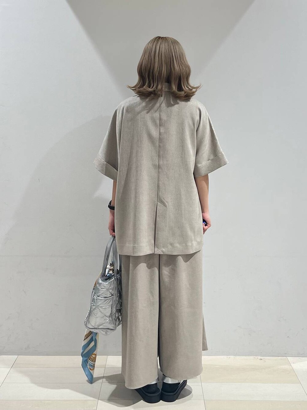 シルバー系のトートバッグ、ホワイト系のキャミソール、シルバー系のサンダルを着用したレディースの夏コーディネートの4枚目の写真