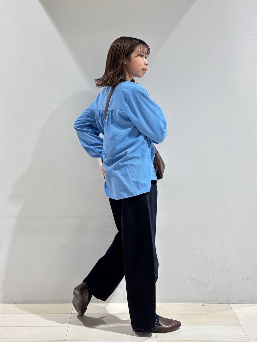 ブルー系のデニムパンツ、ブラウン系のショルダーバッグ、ブルー系のシャツ/ブラウスを着用したレディースの春コーディネートの7枚目の写真