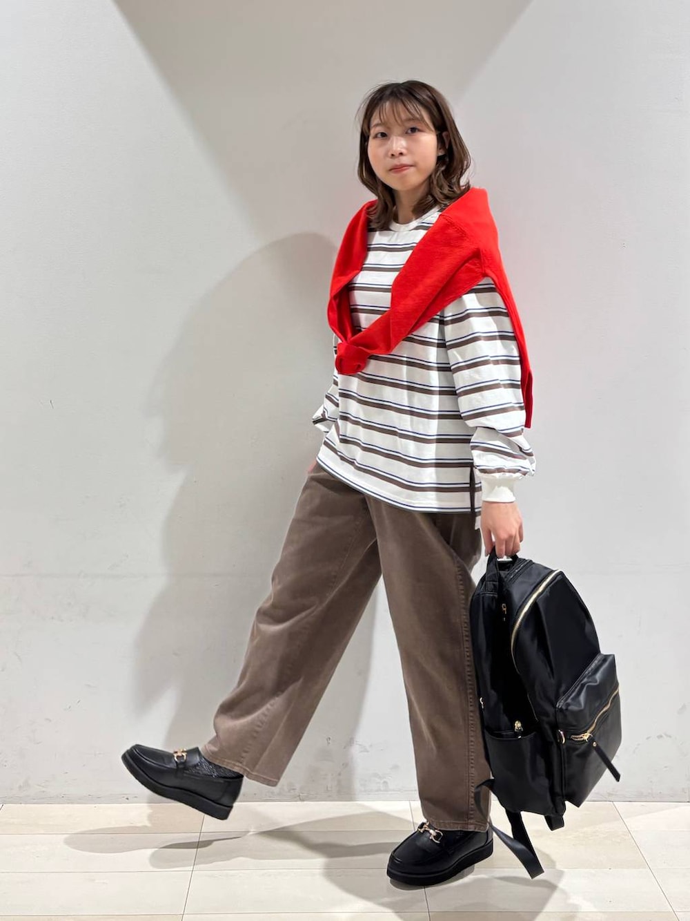 ブラック系のローファー、ブラック系のバックパック/リュック、ブラウン系のデニムパンツを着用したレディースの春コーディネートの3枚目の写真