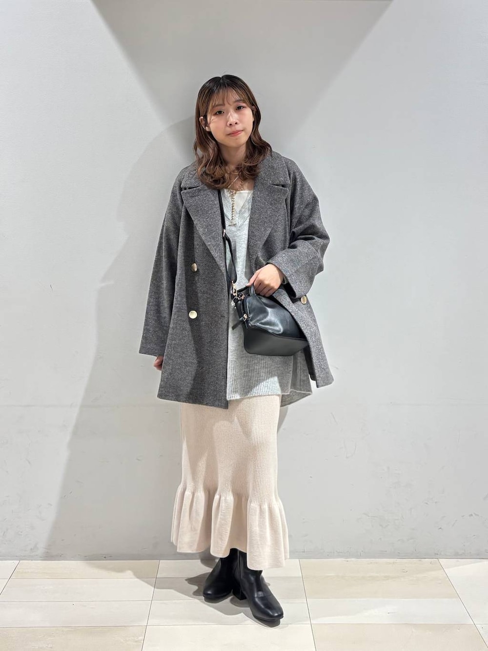 ブラック系のショルダーバッグ、グレー系のチェスターコート、グレー系のニット/セーターを着用したレディースの冬コーディネートの2枚目の写真