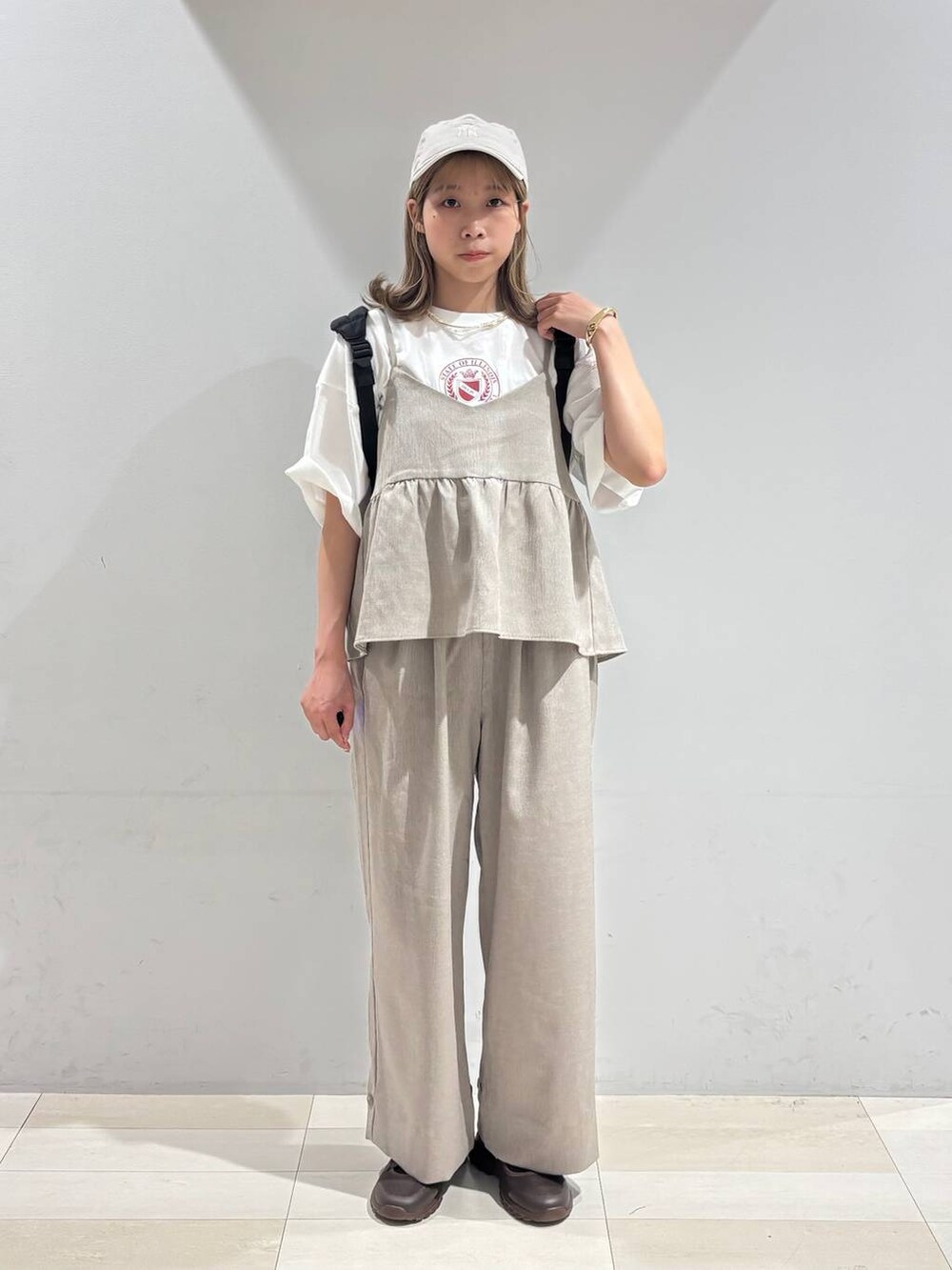 ブラウン系のスニーカー、ブラック系のバックパック/リュック、ベージュ系のサロペット/オーバーオールを着用したレディースの夏コーディネートの3枚目の写真