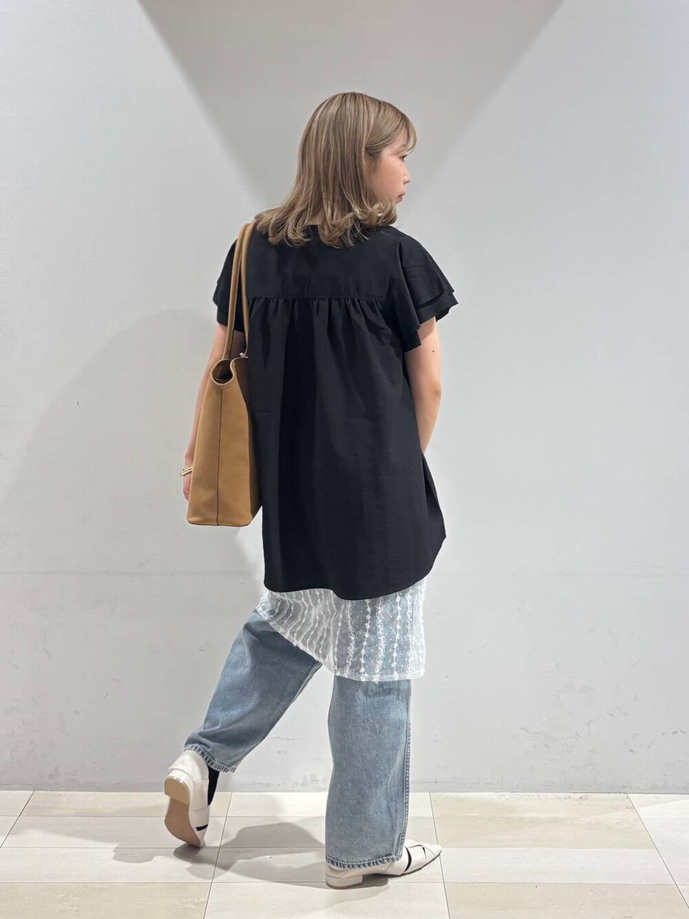 ブルー系のデニムパンツ、ホワイト系のパンプス、ベージュ系のトートバッグを着用したレディースの夏コーディネートの7枚目の写真