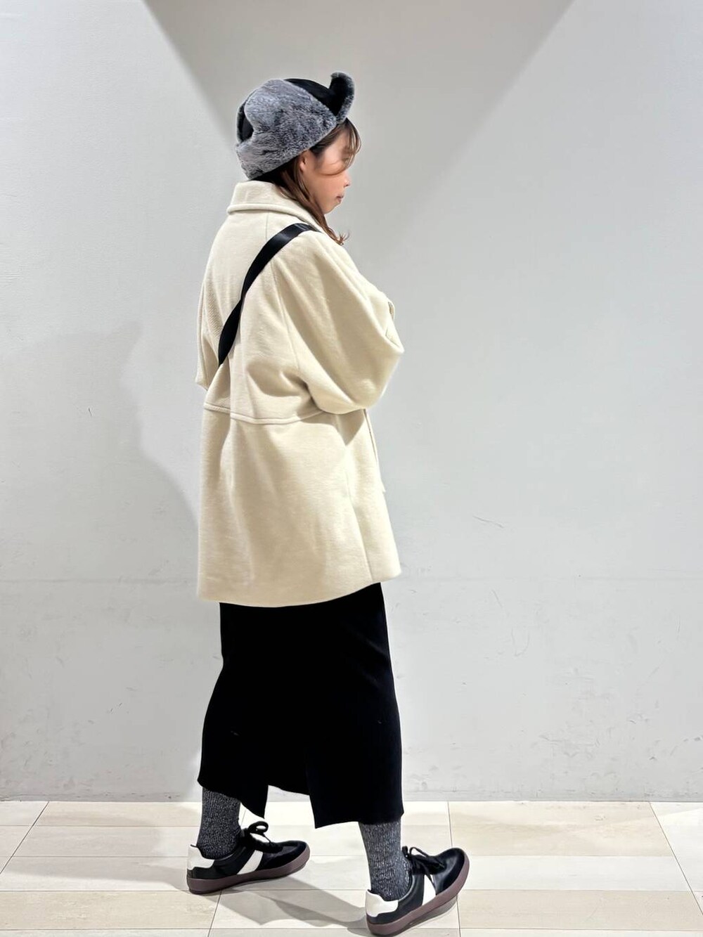 ブラック系のスニーカー、ブラック系のハンドバッグ、ブラック系のスカートを着用したレディースの冬コーディネートの7枚目の写真