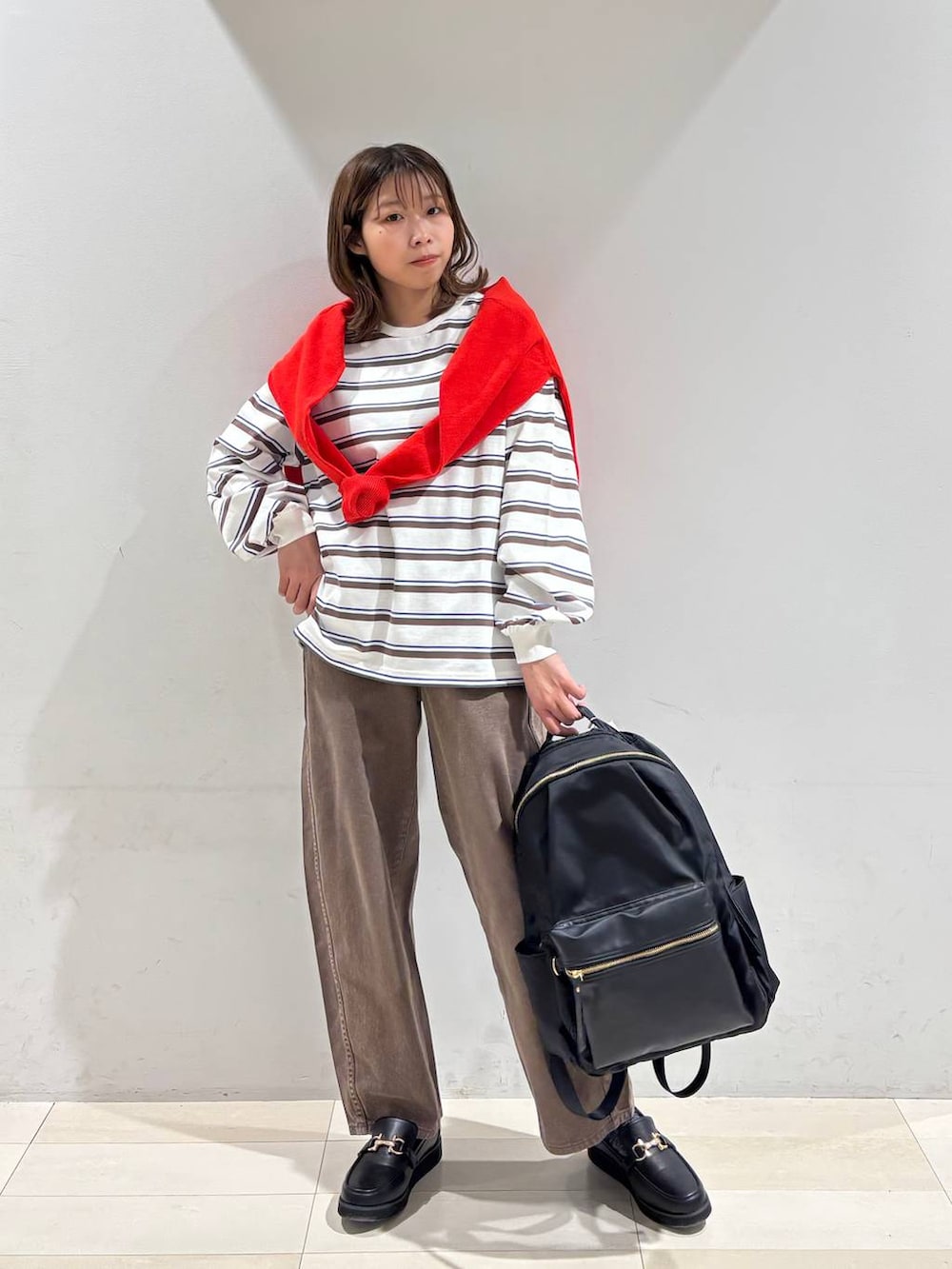 ブラック系のローファー、ブラック系のバックパック/リュック、ブラウン系のデニムパンツを着用したレディースの春コーディネートの5枚目の写真