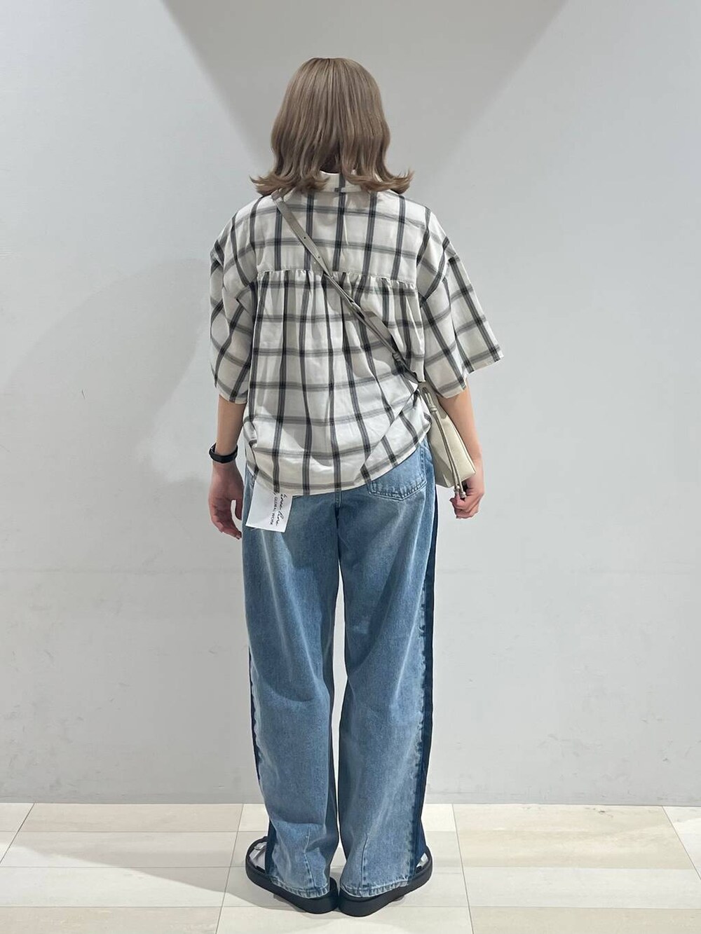 シルバー系のサンダル、ベージュ系のショルダーバッグ、ブルー系のデニムパンツを着用したレディースの夏コーディネートの3枚目の写真