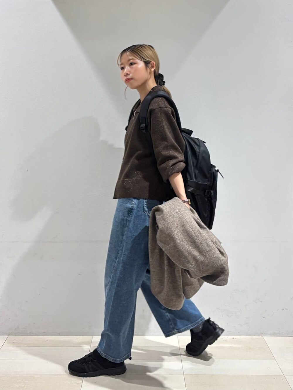 ブラック系のバックパック/リュック、ブラウン系のチェスターコート、ブラウン系のワンピースを着用したレディースの秋コーディネートの5枚目の写真