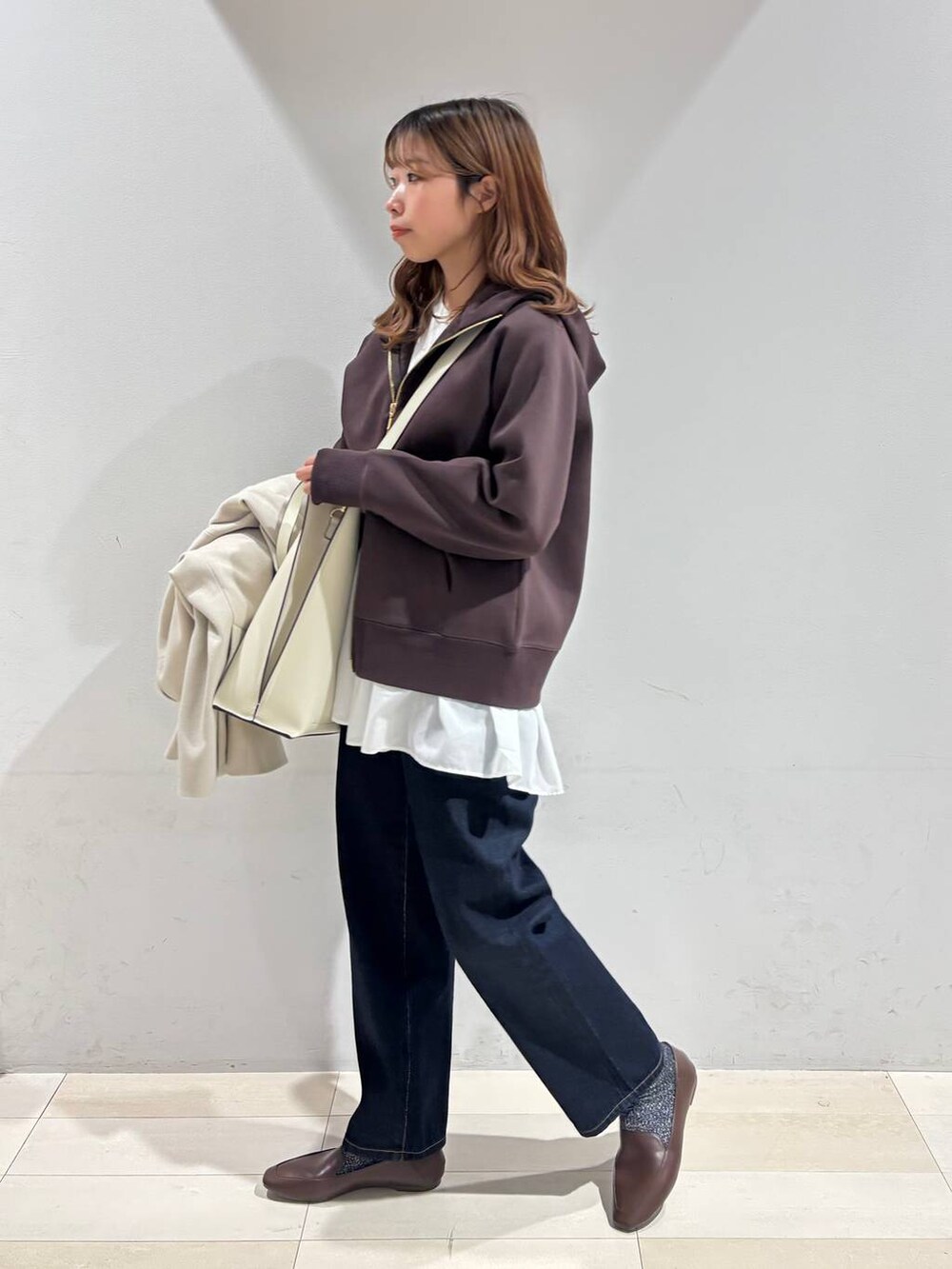 ホワイト系のトートバッグ、ブルー系のデニムパンツ、ベージュ系のテーラードジャケットを着用したレディースの冬コーディネートの4枚目の写真