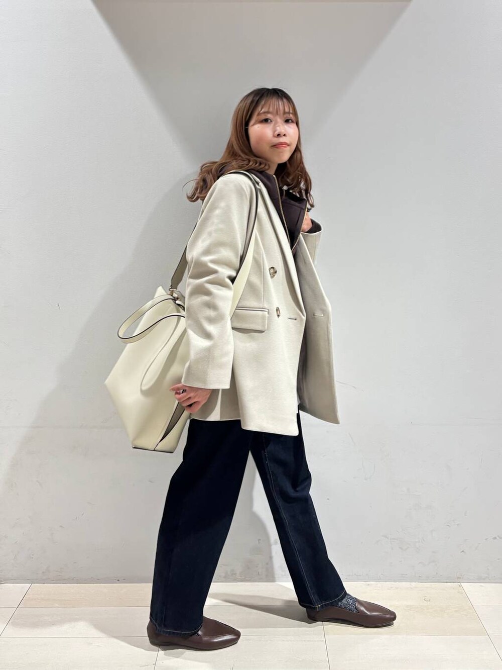 ホワイト系のトートバッグ、ブルー系のデニムパンツ、ベージュ系のテーラードジャケットを着用したレディースの冬コーディネートの6枚目の写真