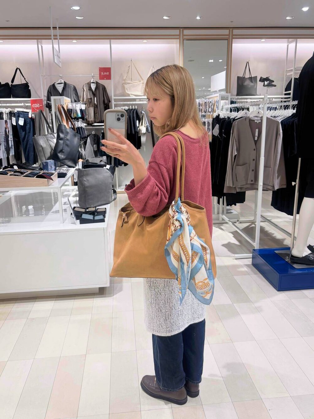 ブルー系のデニムパンツ、ブラウン系のローファー、ベージュ系のトートバッグを着用したレディースの秋コーディネートの2枚目の写真