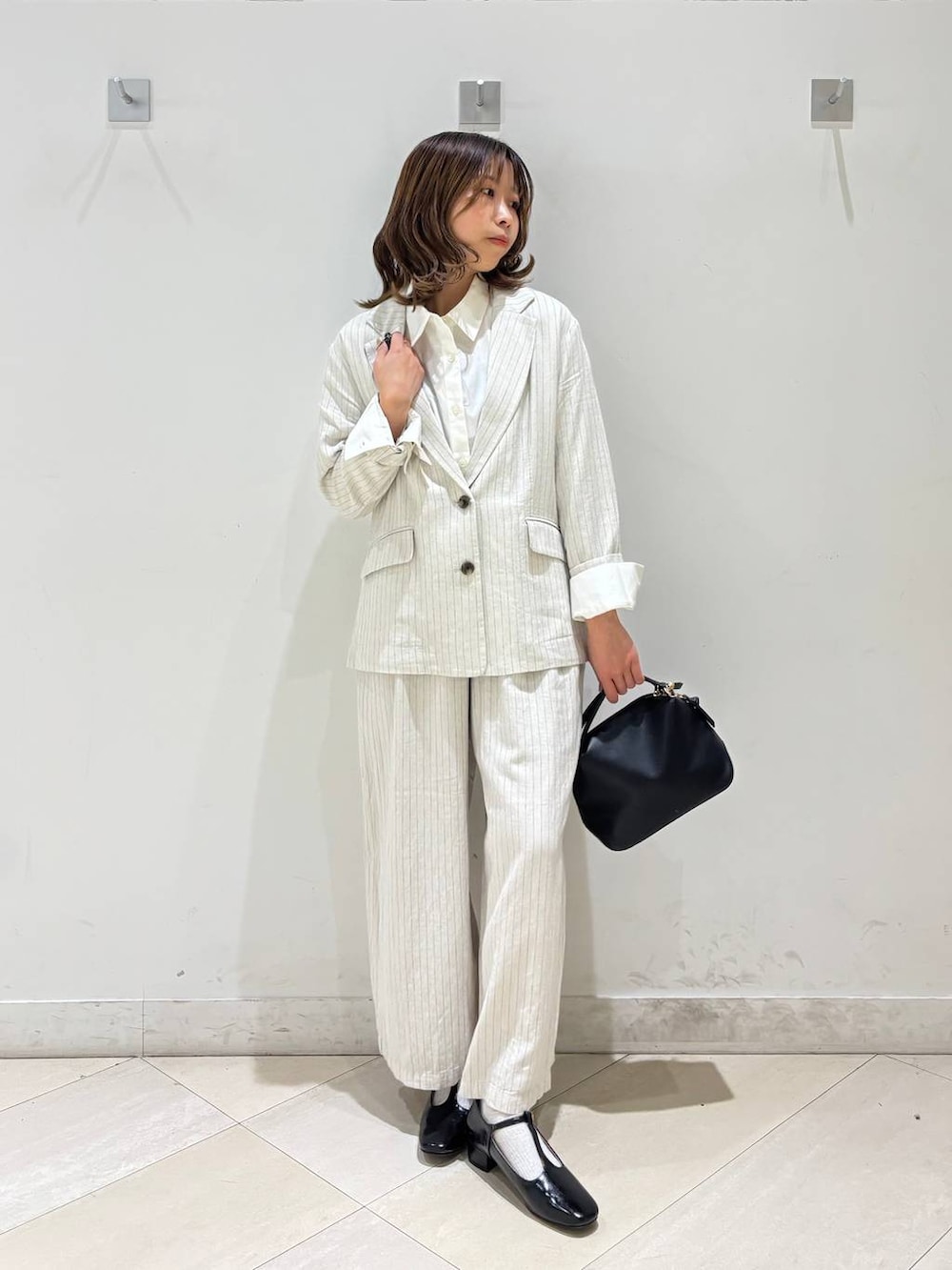 ブラック系のショルダーバッグ、ベージュ系のその他パンツ、グレー系のテーラードジャケットを着用したレディースの春コーディネートの8枚目の写真