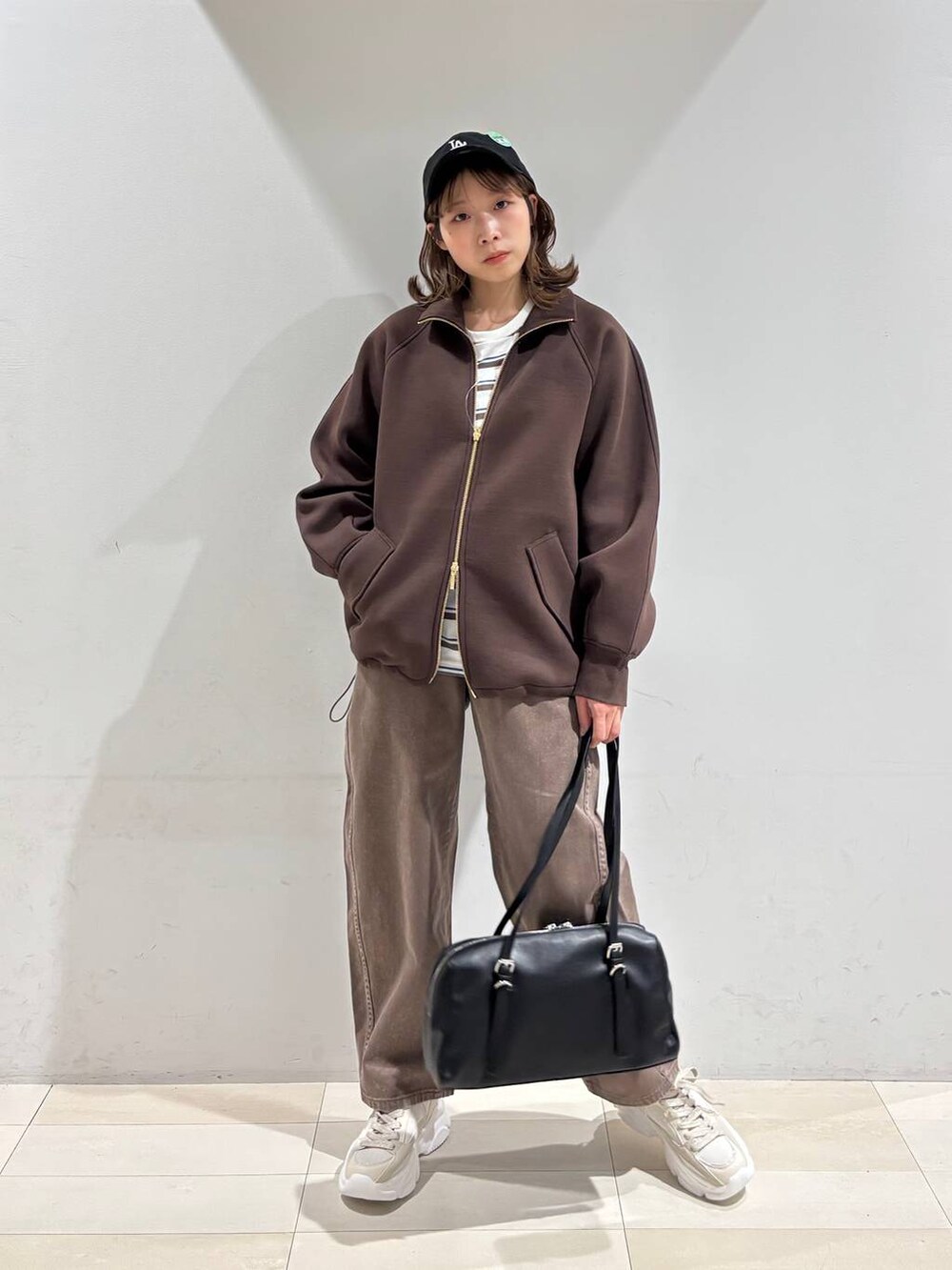 ブラウン系のデニムパンツ、ブラウン系のブルゾン、ゴールド系のスニーカーを着用したレディースの春コーディネートの7枚目の写真