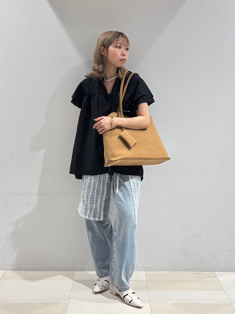 ブルー系のデニムパンツ、ホワイト系のパンプス、ベージュ系のトートバッグを着用したレディースの夏コーディネートの9枚目の写真