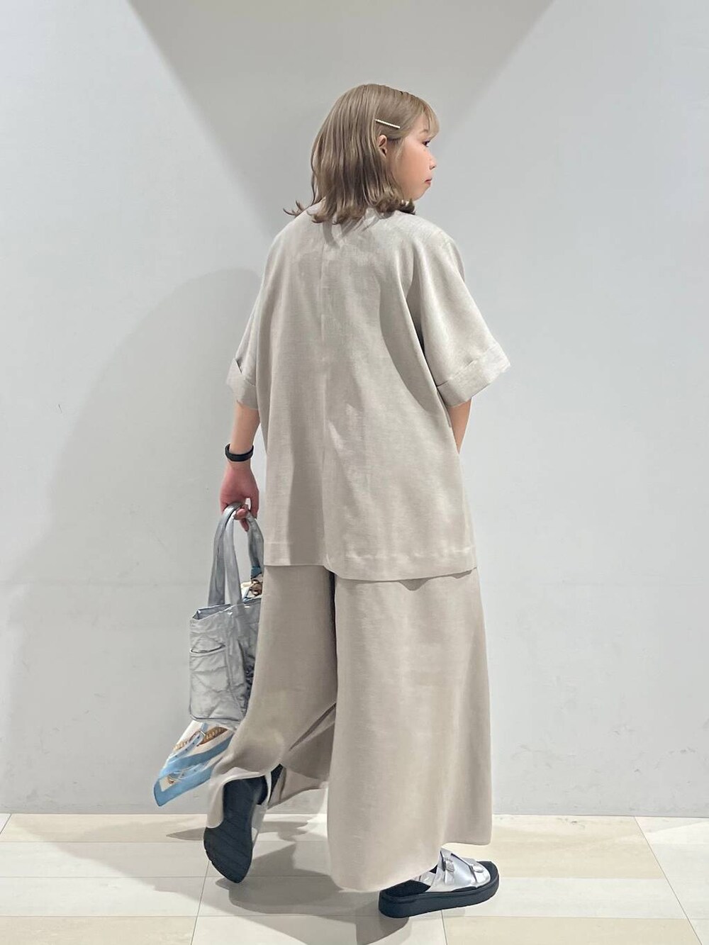 シルバー系のトートバッグ、ホワイト系のキャミソール、シルバー系のサンダルを着用したレディースの夏コーディネートの6枚目の写真