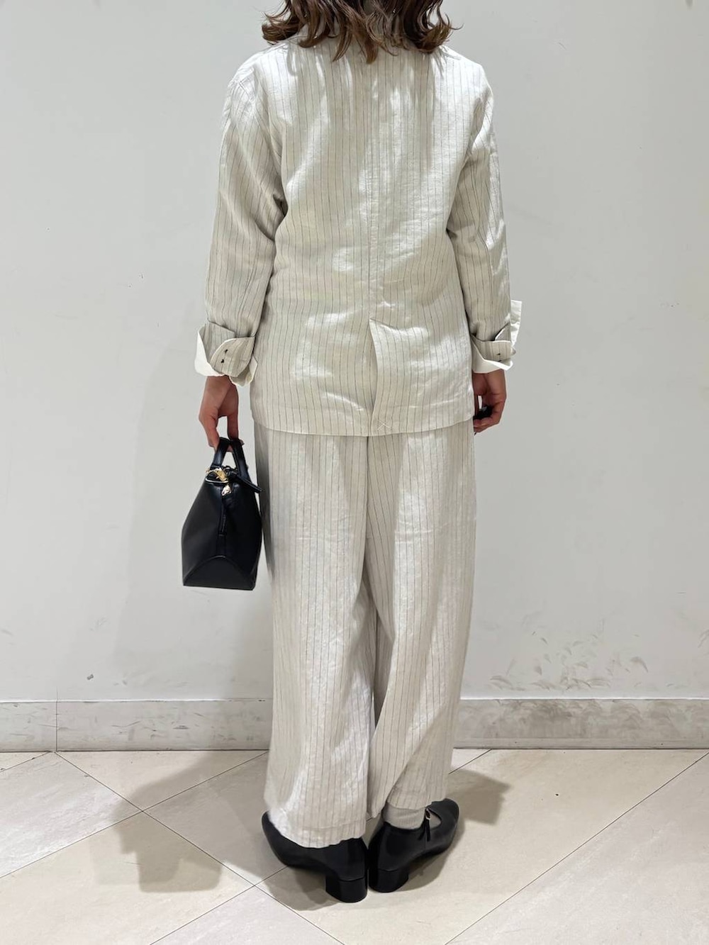 ブラック系のショルダーバッグ、ベージュ系のその他パンツ、グレー系のテーラードジャケットを着用したレディースの春コーディネートの5枚目の写真