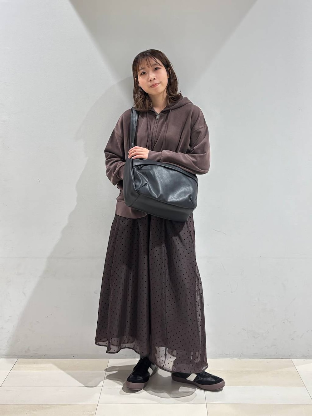 ブラック系のスニーカー、ブラック系のショルダーバッグ、ブラウン系のスカートを着用したレディースの春コーディネートの7枚目の写真