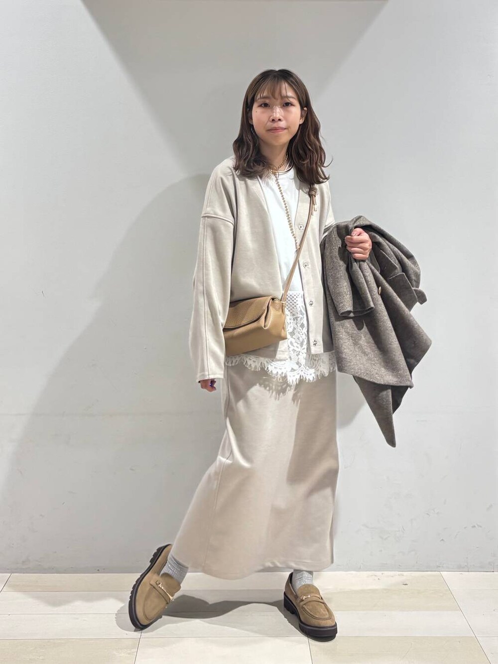 ブラウン系のチェスターコート、ベージュ系のローファー、ベージュ系のショルダーバッグを着用したレディースの秋コーディネートの6枚目の写真
