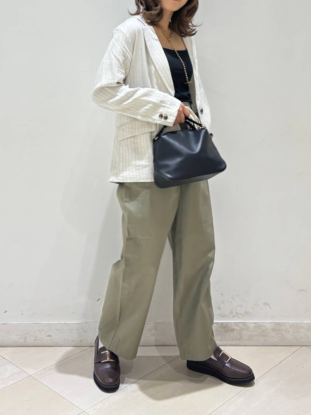 ブラック系のショルダーバッグ、ブラウン系のローファー、ブラック系のキャミソールを着用したレディースの春コーディネートの3枚目の写真