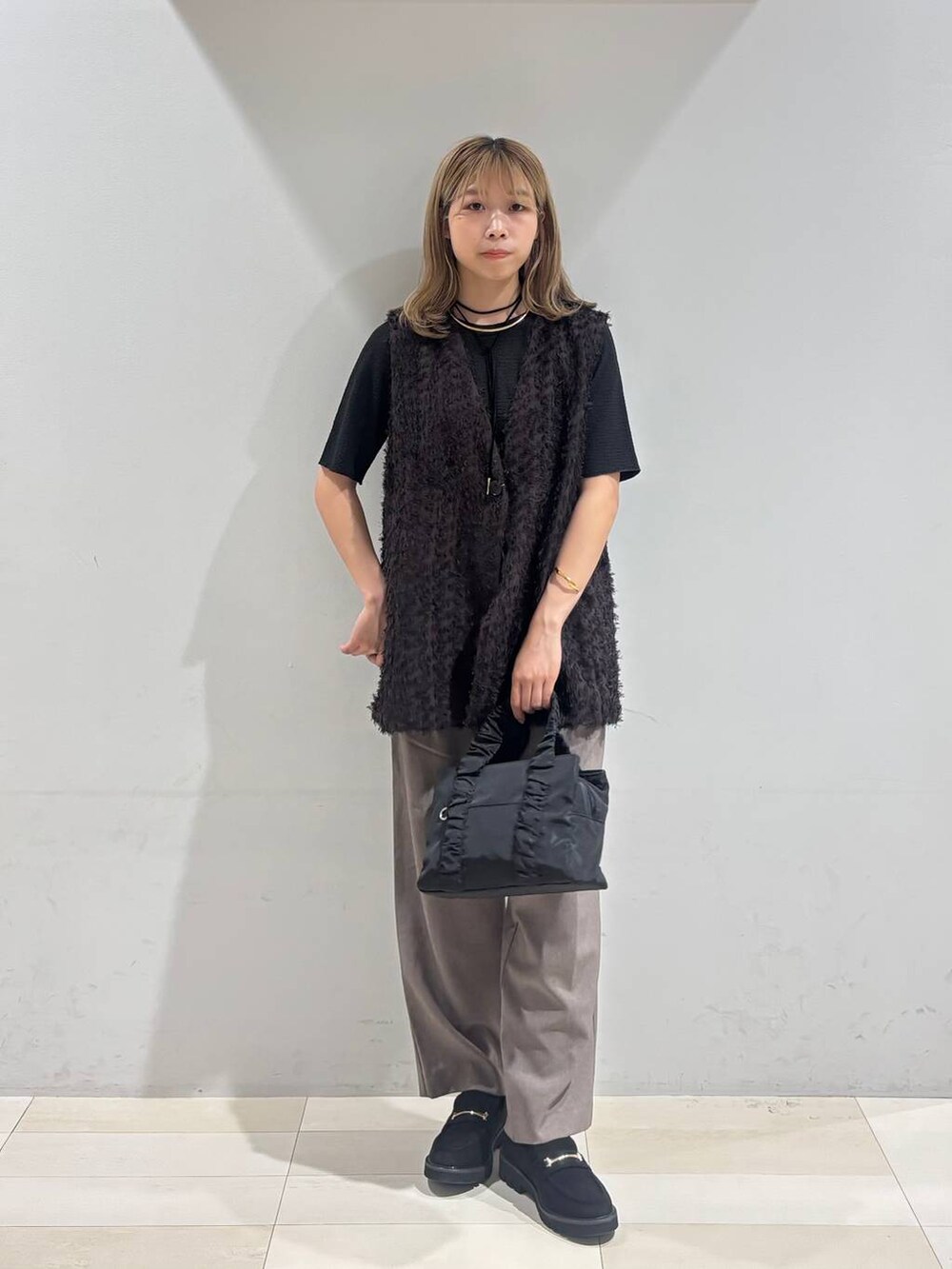 ブラック系のショルダーバッグ、ブラック系のTシャツ/カットソー、ブラック系のローファーを着用したレディースの秋コーディネートの2枚目の写真