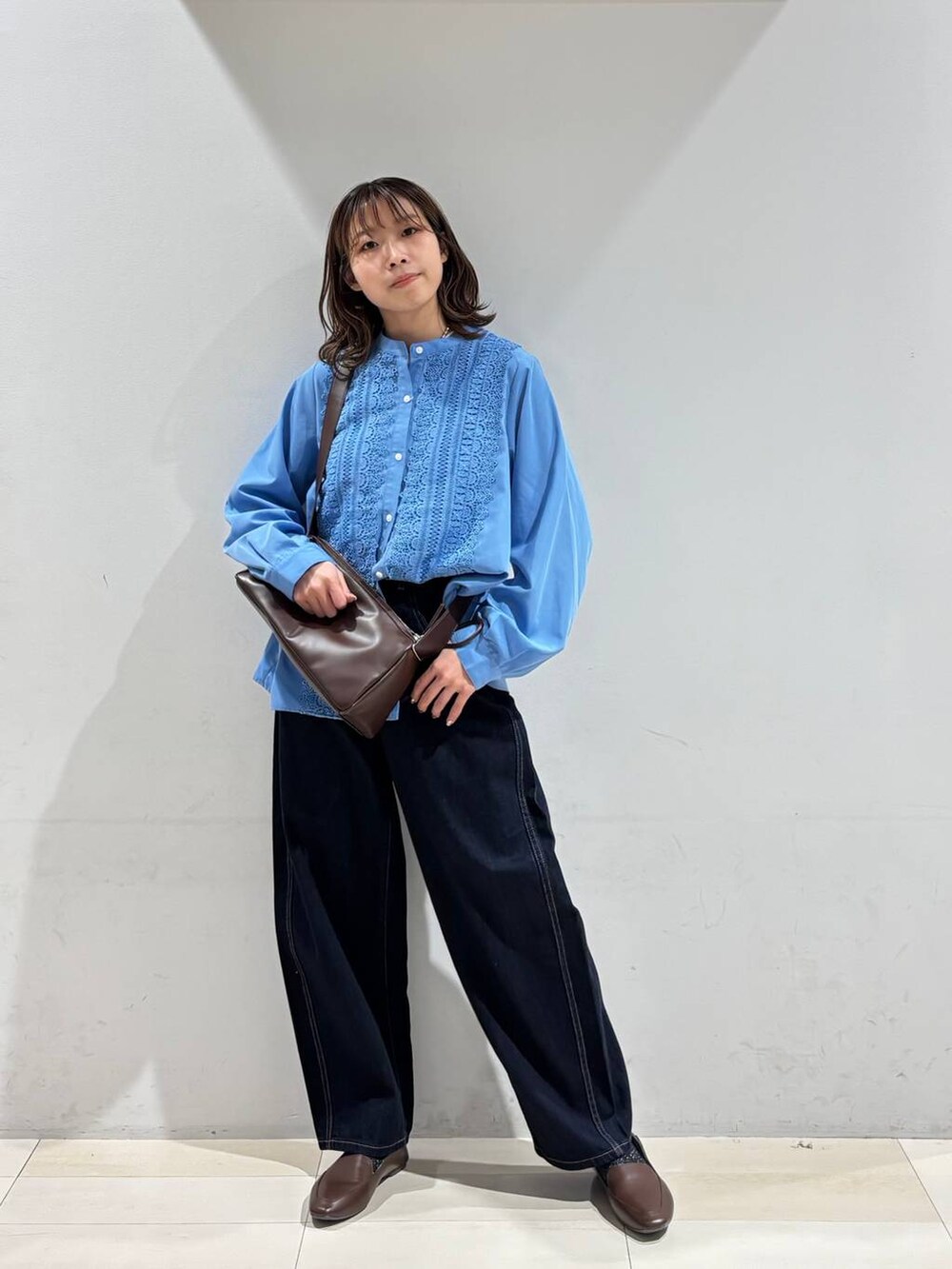 ブルー系のデニムパンツ、ブラウン系のショルダーバッグ、ブルー系のシャツ/ブラウスを着用したレディースの春コーディネートの9枚目の写真