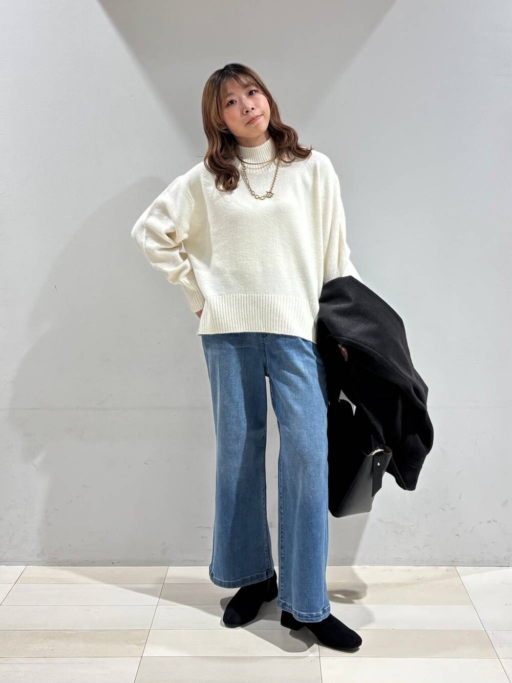 ブラック系のショルダーバッグ、ブラック系のチェスターコート、ホワイト系のニット/セーターを着用したレディースの冬コーディネートの6枚目の写真