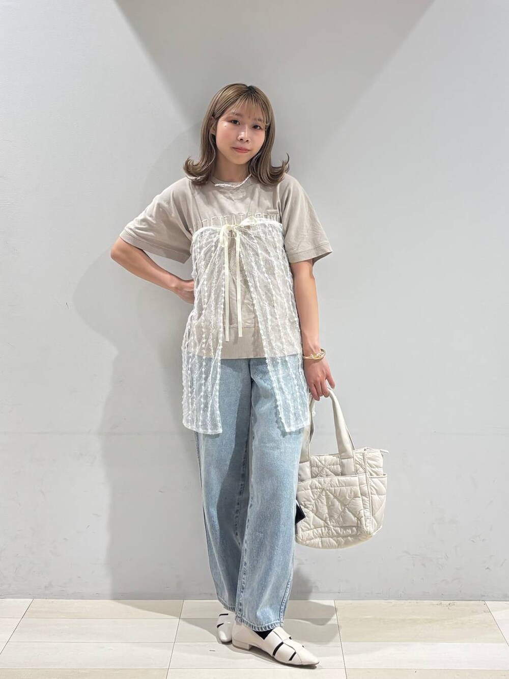 ブルー系のデニムパンツ、ホワイト系のトートバッグ、ホワイト系のパンプスを着用したレディースの夏コーディネートの6枚目の写真