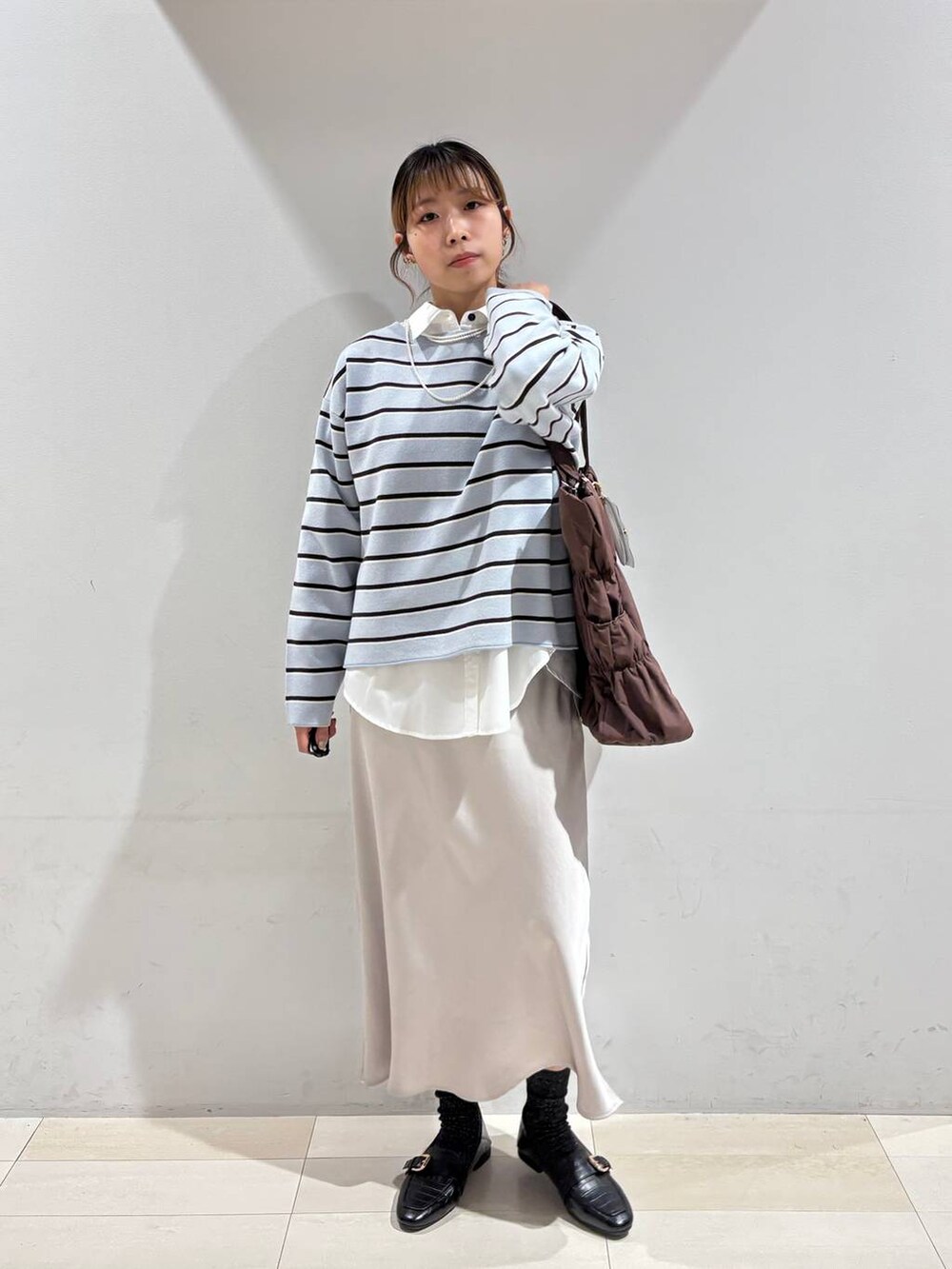 ブラック系のローファー、ブラウン系のトートバッグ、ブルー系のニット/セーターを着用したレディースの冬コーディネートの2枚目の写真