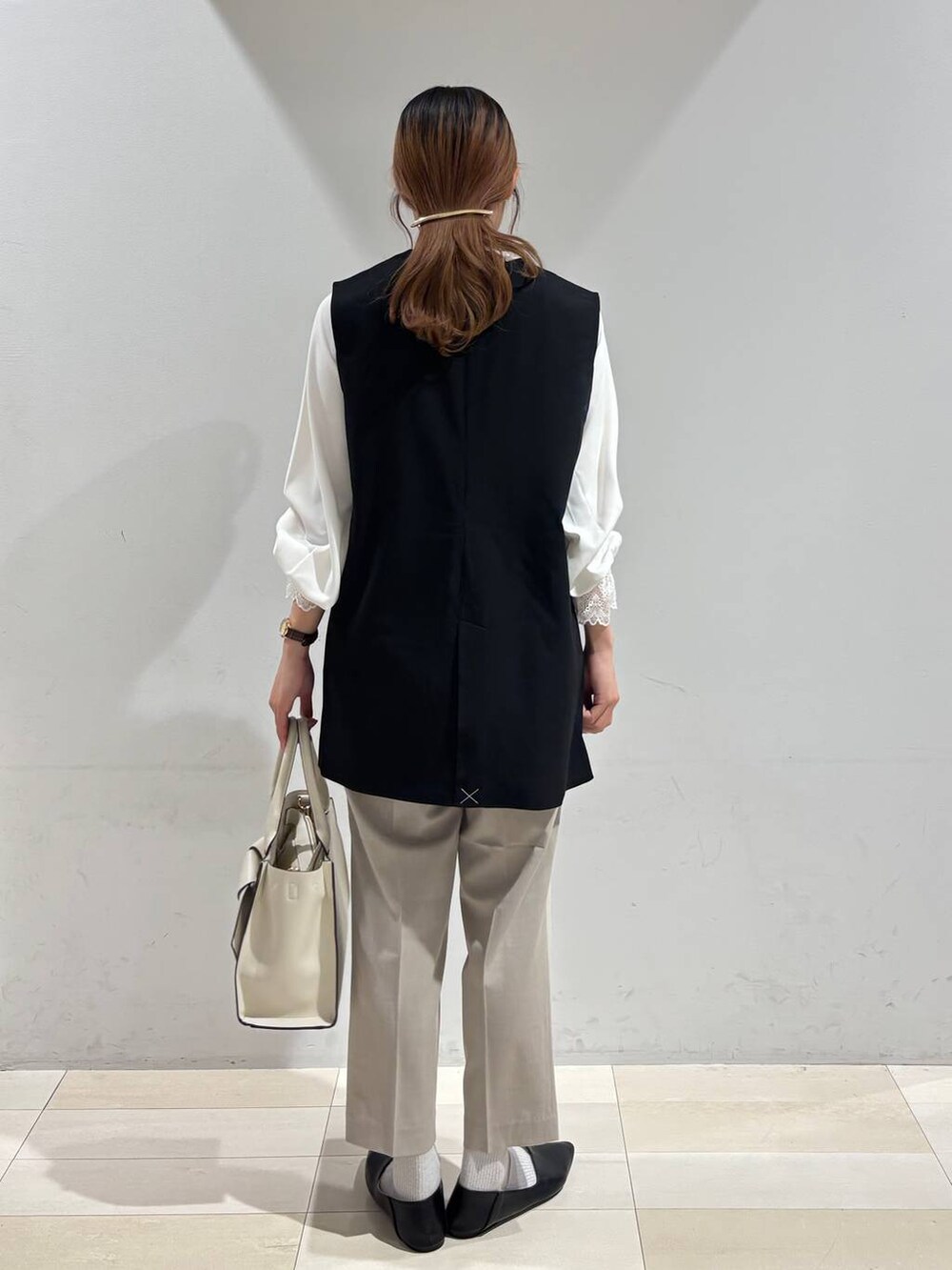 ブラック系のパンプス、ベージュ系のスラックス、ホワイト系のシャツ/ブラウスを着用したレディースの冬コーディネートの3枚目の写真