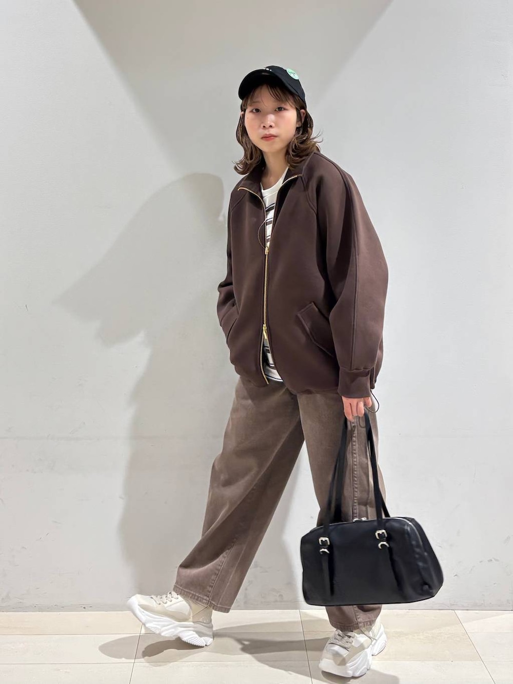 ブラウン系のデニムパンツ、ブラウン系のブルゾン、ゴールド系のスニーカーを着用したレディースの春コーディネートの8枚目の写真