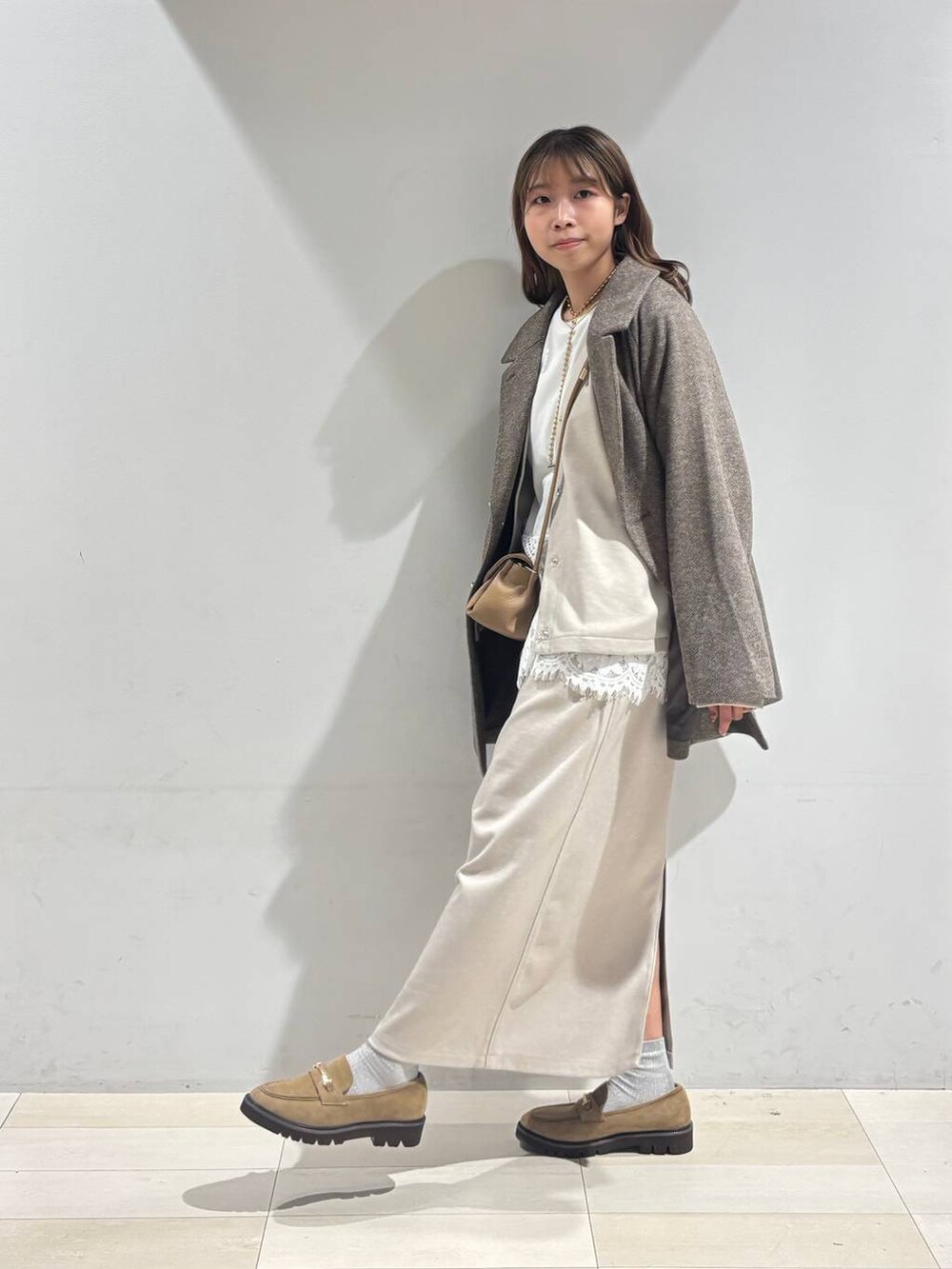 ブラウン系のチェスターコート、ベージュ系のローファー、ベージュ系のショルダーバッグを着用したレディースの秋コーディネートの4枚目の写真