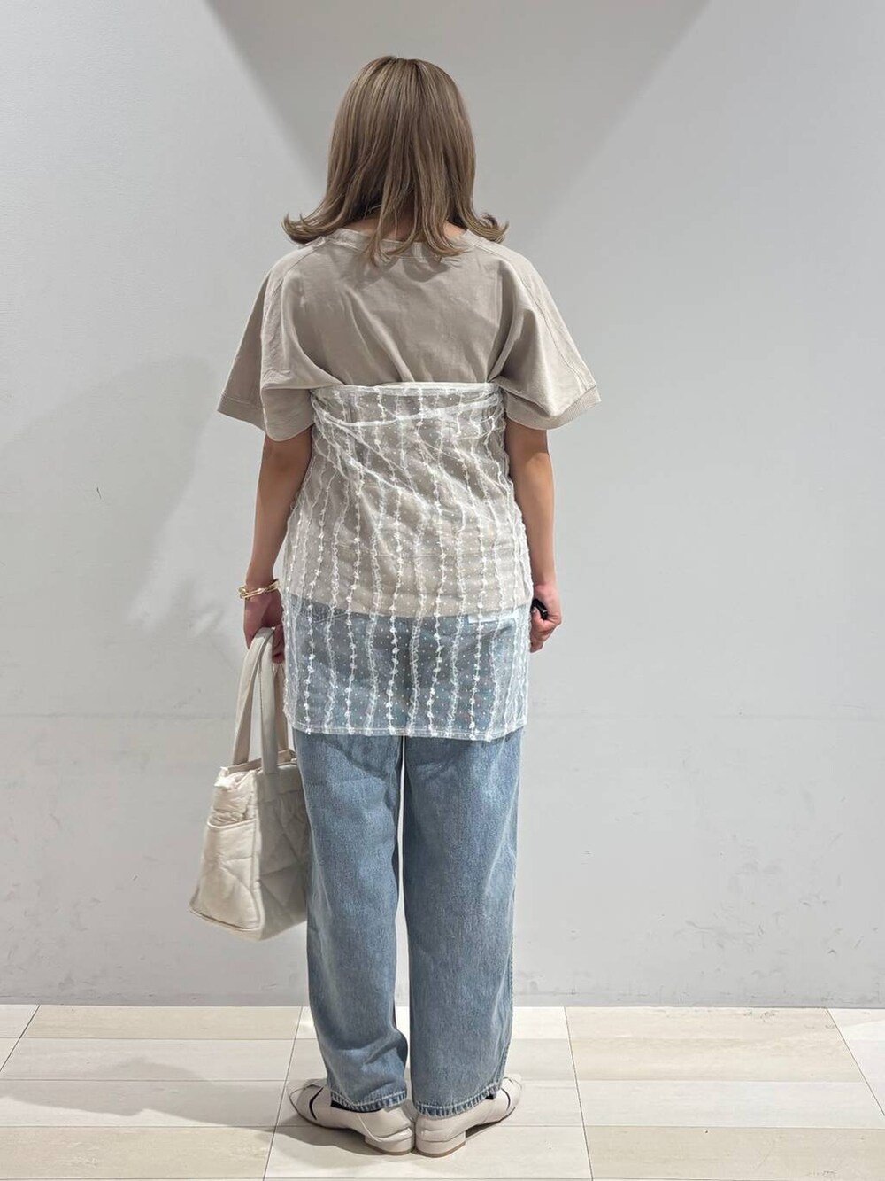 ブルー系のデニムパンツ、ホワイト系のトートバッグ、ホワイト系のパンプスを着用したレディースの夏コーディネートの3枚目の写真