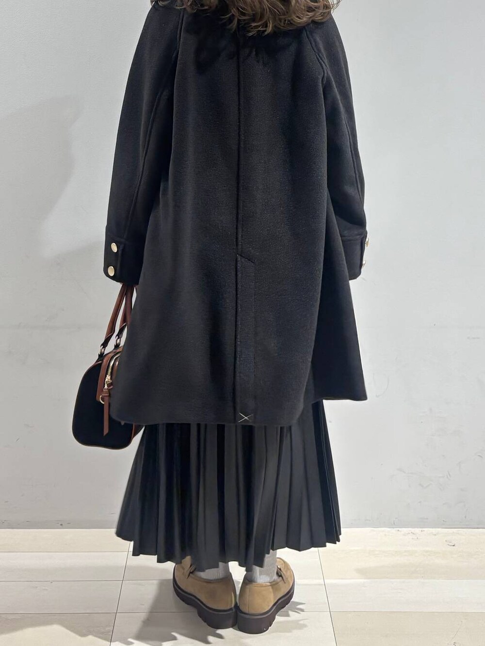 ブラック系のチェスターコート、ベージュ系のローファー、ブラック系のスカートを着用したレディースの秋コーディネートの5枚目の写真