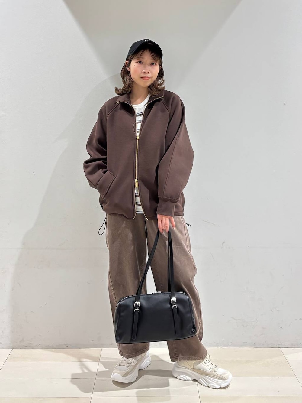 ブラウン系のデニムパンツ、ブラウン系のブルゾン、ゴールド系のスニーカーを着用したレディースの春コーディネートの9枚目の写真