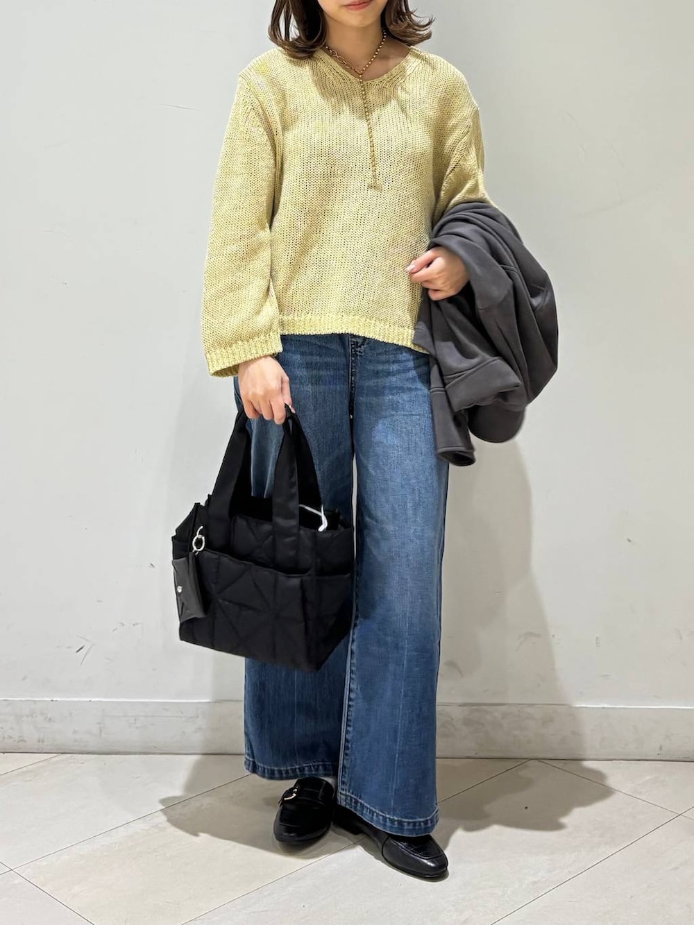 ブラック系のローファー、ブラック系のトートバッグ、ブルー系のデニムパンツを着用したレディースの春コーディネートの2枚目の写真