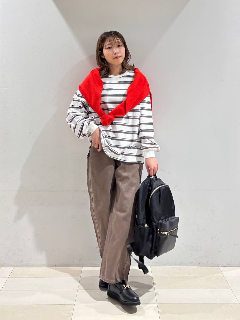 ブラック系のローファー、ブラック系のバックパック/リュック、ブラウン系のデニムパンツを着用したレディースの春コーディネートの8枚目の写真