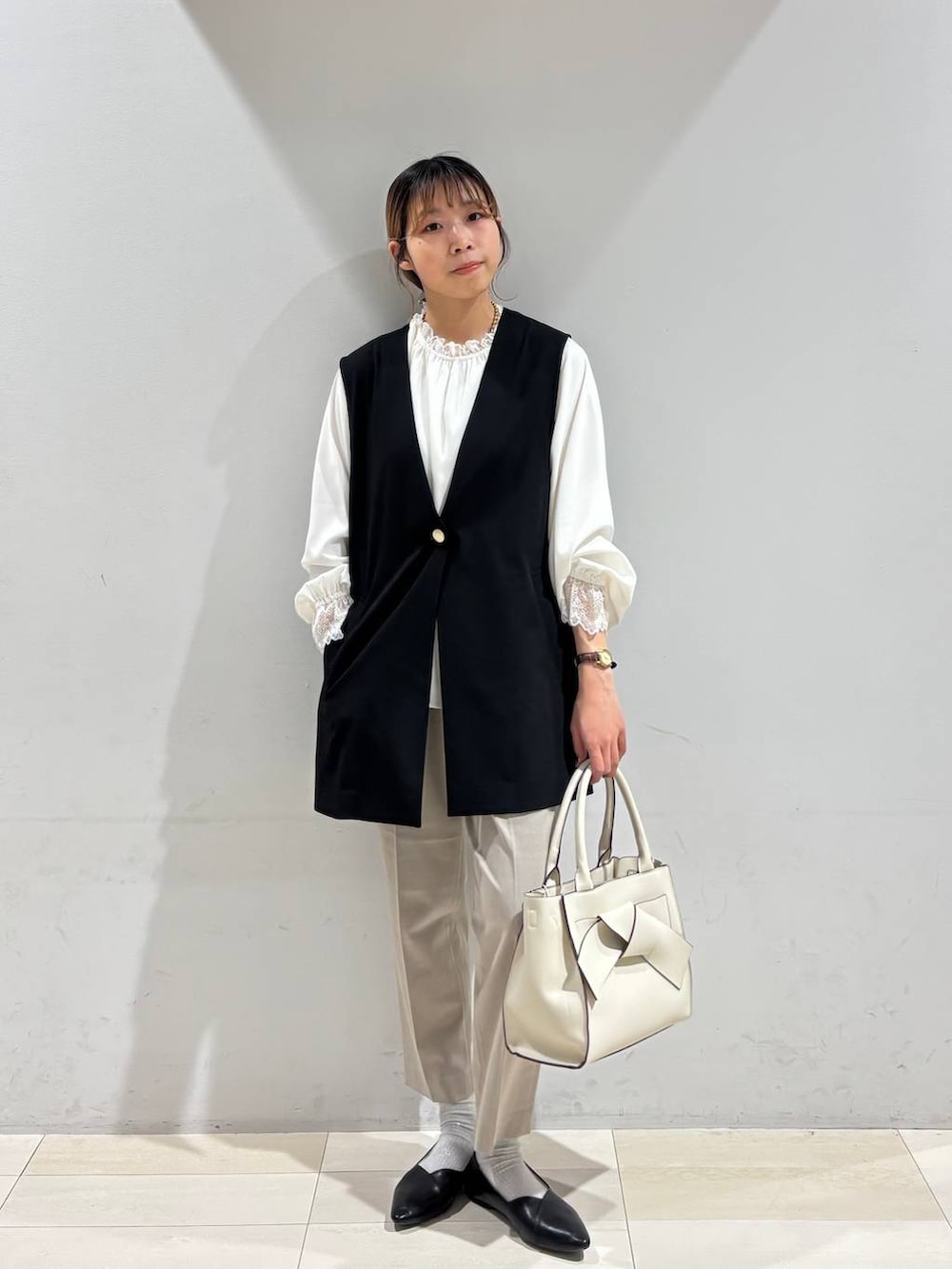 ブラック系のパンプス、ベージュ系のスラックス、ホワイト系のシャツ/ブラウスを着用したレディースの冬コーディネートの6枚目の写真