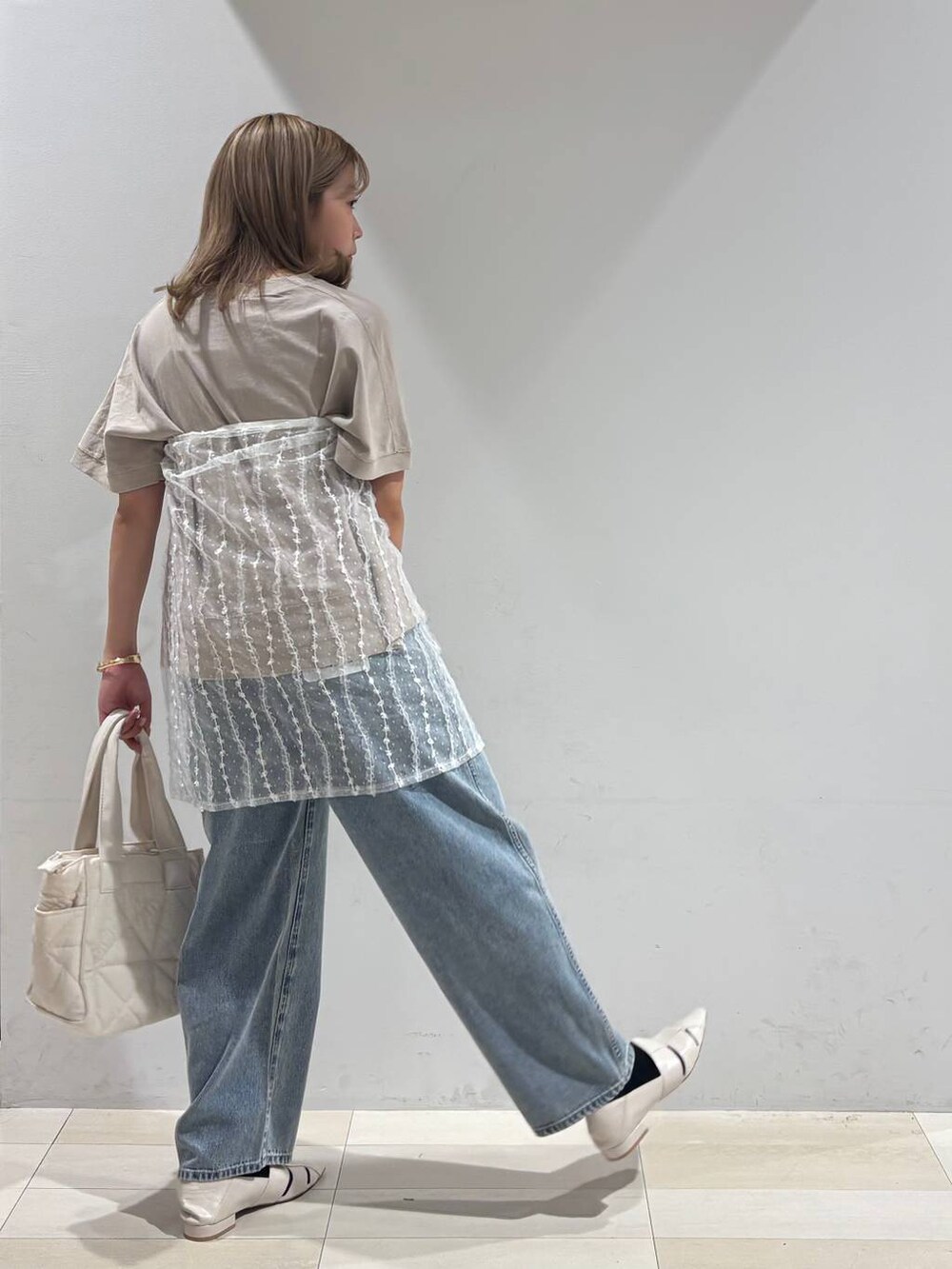 ブルー系のデニムパンツ、ホワイト系のトートバッグ、ホワイト系のパンプスを着用したレディースの夏コーディネートの4枚目の写真
