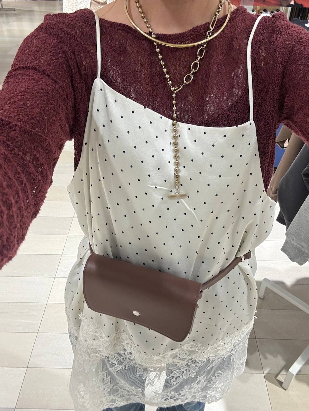 レッド系のTシャツ/カットソー、ブラウン系のボディバッグ/ウエストポーチ、ホワイト系のキャミソールを着用したレディースの秋コーディネートの4枚目の写真