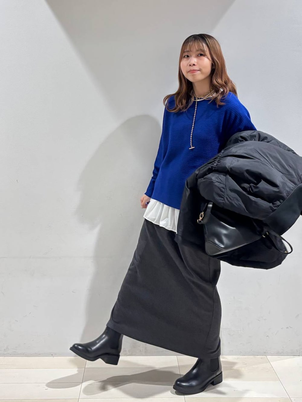 ブラック系のショルダーバッグ、ブラック系のダウンジャケット/コート、ホワイト系のTシャツ/カットソーを着用したレディースの冬コーディネートの4枚目の写真