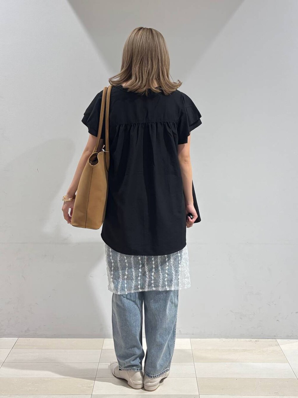 ブルー系のデニムパンツ、ホワイト系のパンプス、ベージュ系のトートバッグを着用したレディースの夏コーディネートの4枚目の写真