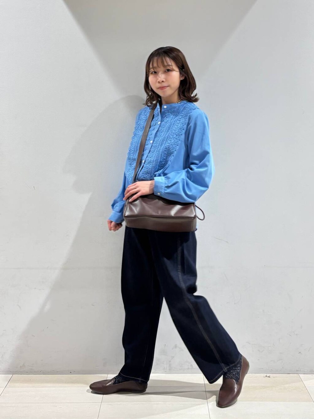 ブルー系のデニムパンツ、ブラウン系のショルダーバッグ、ブルー系のシャツ/ブラウスを着用したレディースの春コーディネートの4枚目の写真