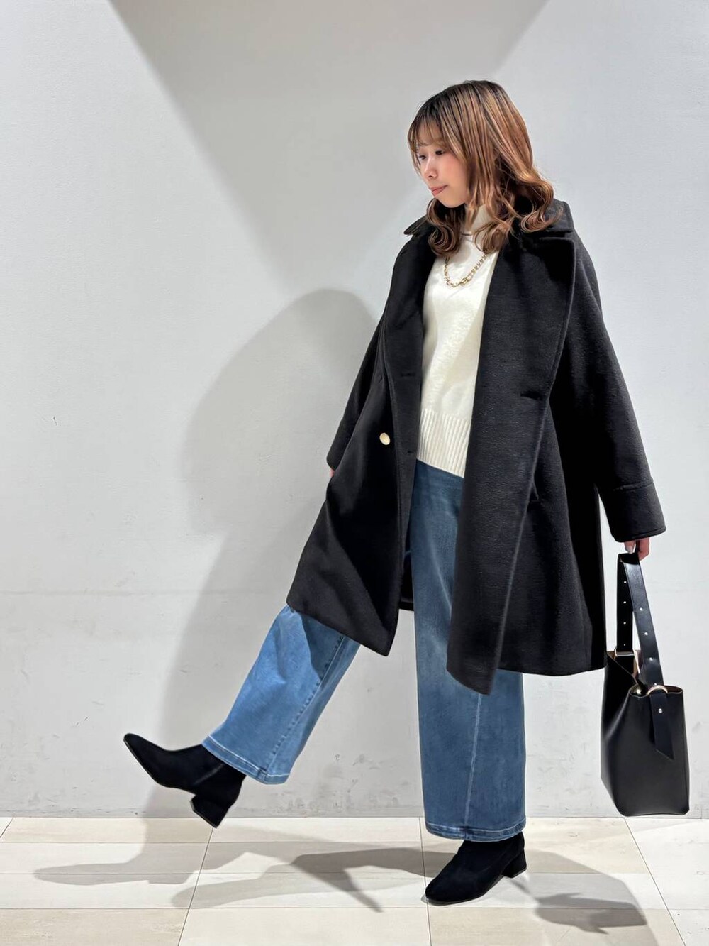 ブラック系のショルダーバッグ、ブラック系のチェスターコート、ホワイト系のニット/セーターを着用したレディースの冬コーディネートの7枚目の写真