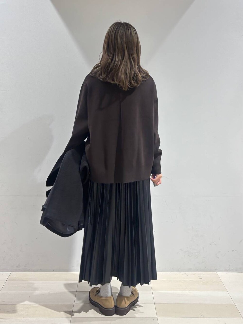 ブラック系のチェスターコート、ベージュ系のローファー、ブラック系のスカートを着用したレディースの秋コーディネートの8枚目の写真