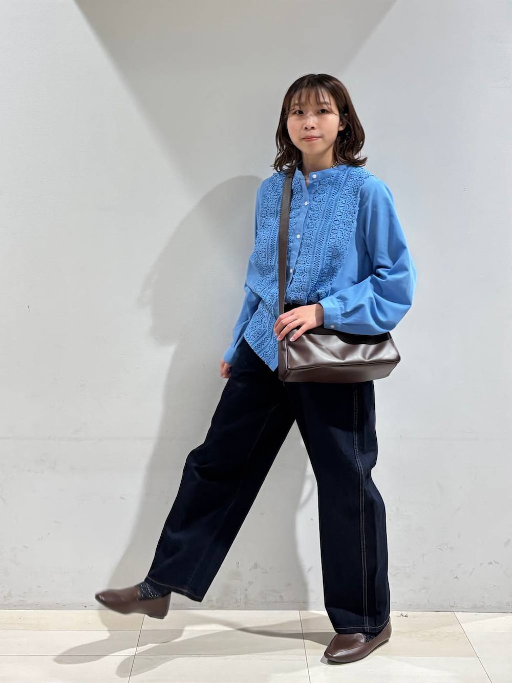 ブルー系のデニムパンツ、ブラウン系のショルダーバッグ、ブルー系のシャツ/ブラウスを着用したレディースの春コーディネートの3枚目の写真