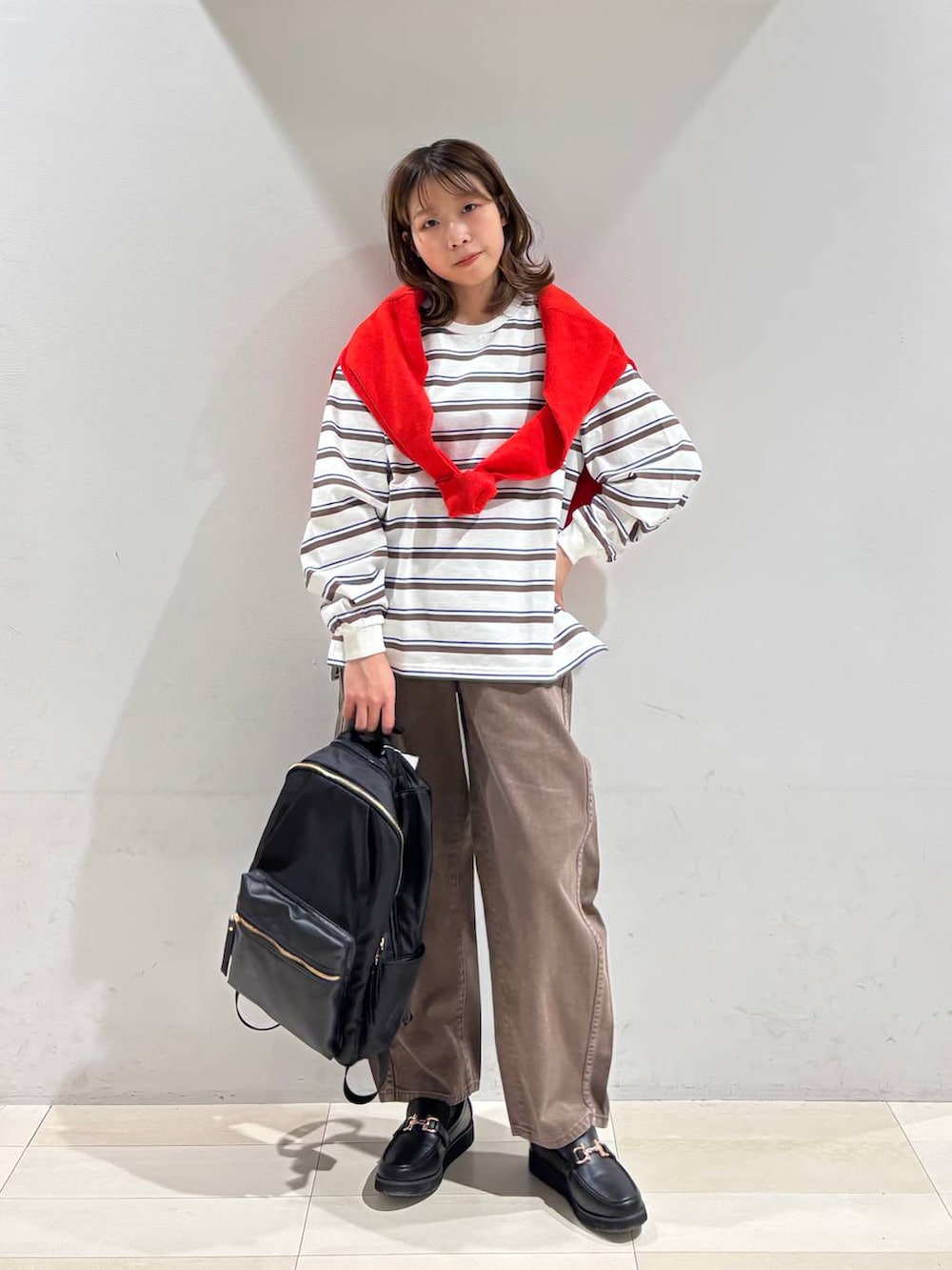 ブラック系のローファー、ブラック系のバックパック/リュック、ブラウン系のデニムパンツを着用したレディースの春コーディネートの2枚目の写真