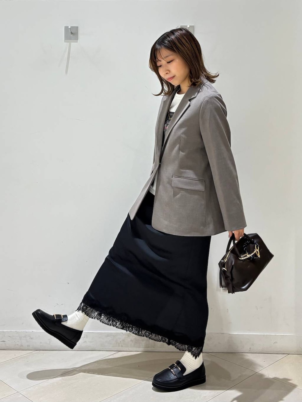 ブラック系のローファー、ブラウン系のテーラードジャケット、ブラウン系のボストンバッグを着用したレディースの春コーディネートの3枚目の写真