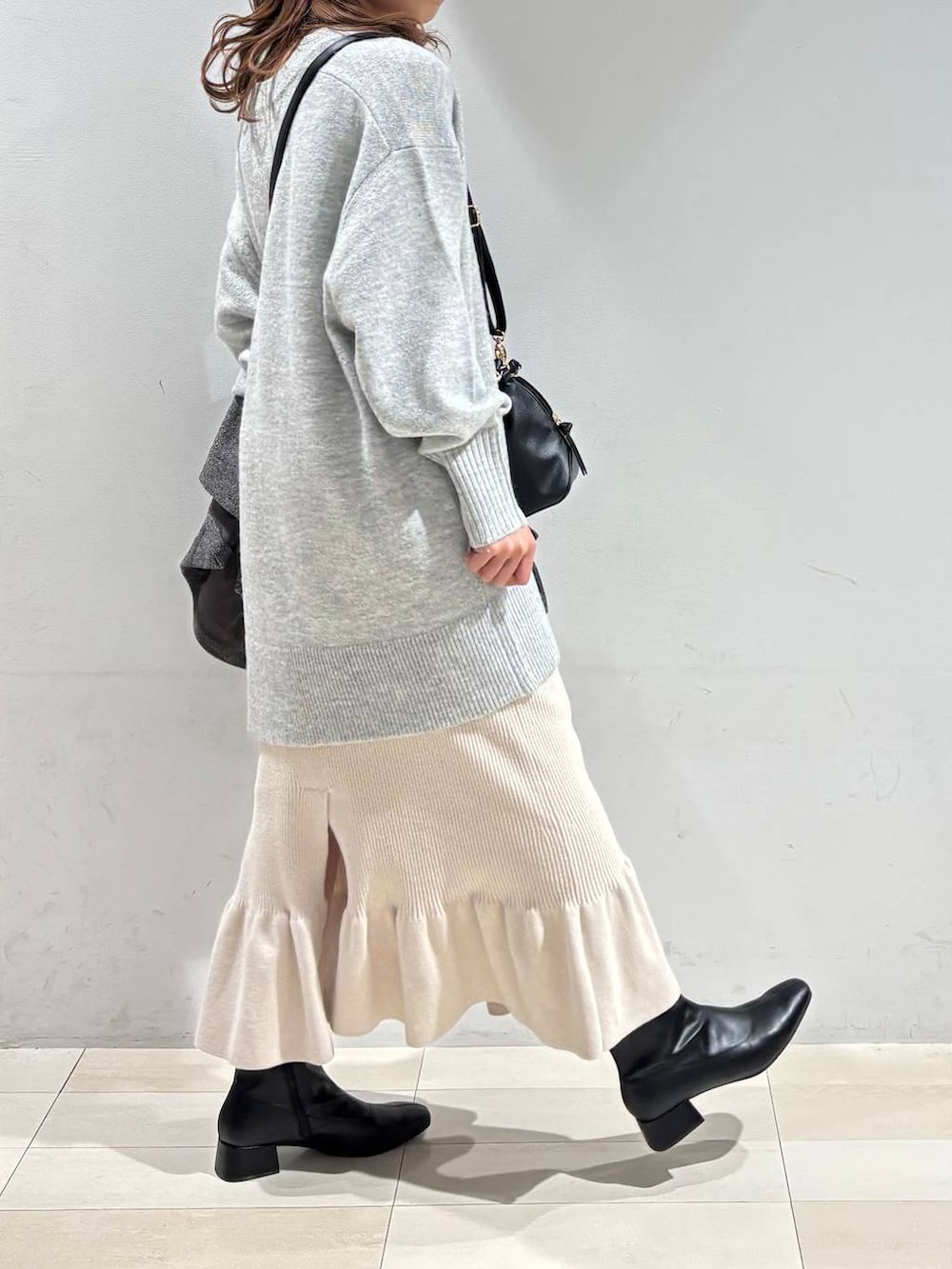 ブラック系のショルダーバッグ、グレー系のチェスターコート、グレー系のニット/セーターを着用したレディースの冬コーディネートの8枚目の写真