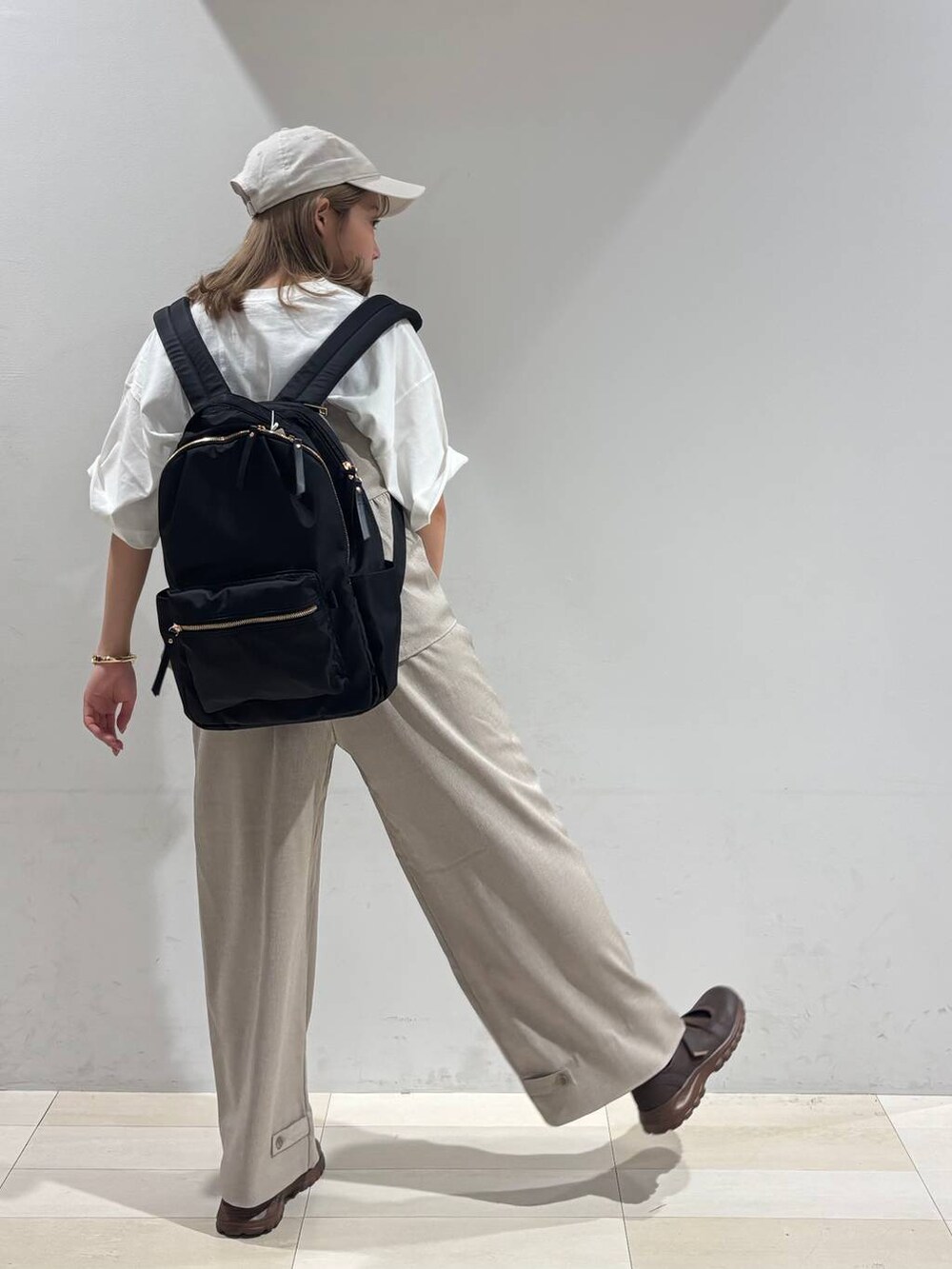 ブラウン系のスニーカー、ブラック系のバックパック/リュック、ベージュ系のサロペット/オーバーオールを着用したレディースの夏コーディネートの6枚目の写真